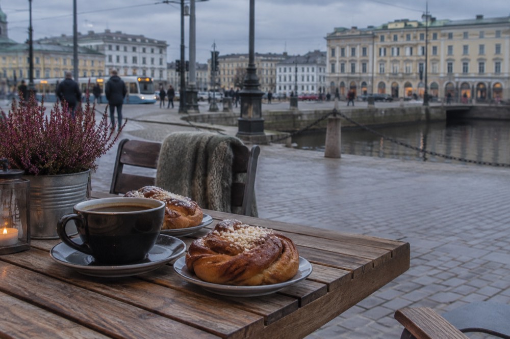 Cinnamon buns and a cup of black coffee on a cafe table in wooden surroundings