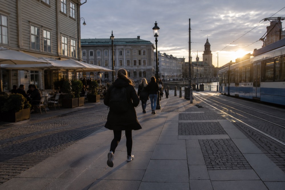 A tram passing through a Gothenburg street with cafes and wooden buildings in the evening light