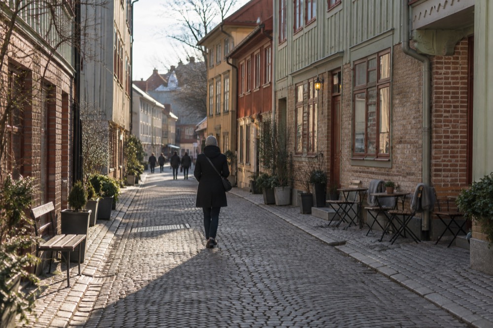 Cobblestone street with wooden houses and café tables in the Haga quarter of Gothenburg