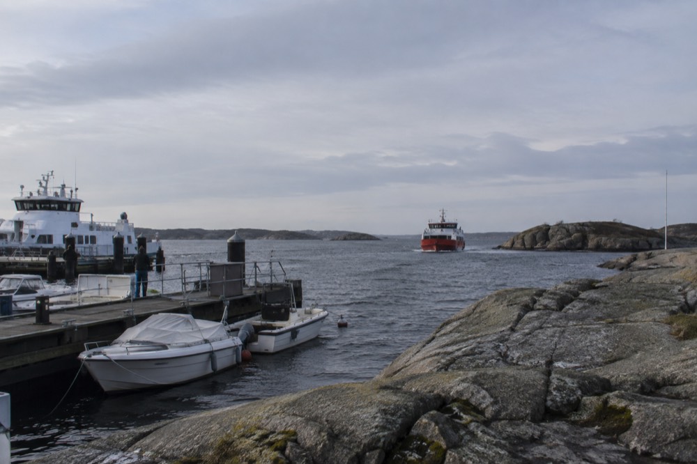 Red ferry boat approaching a small car-free island in the Gothenburg archipelago on a grey sea