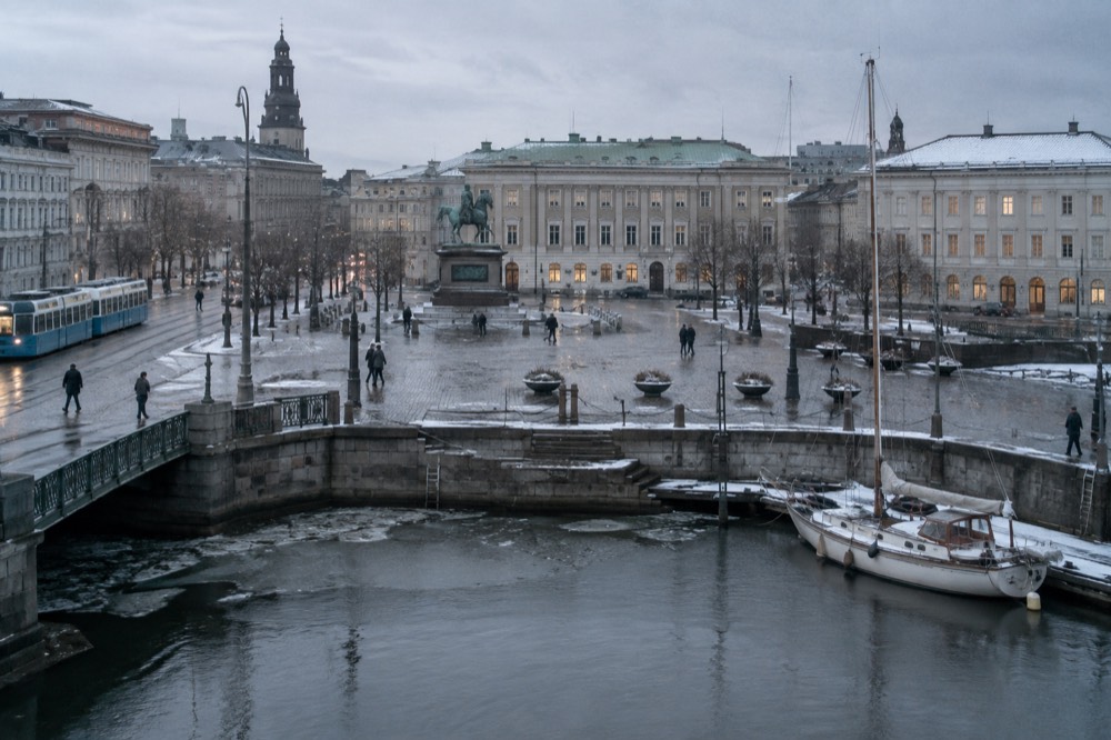 A small sailing boat moored in a frosty Swedish harbour with a grey winter sky