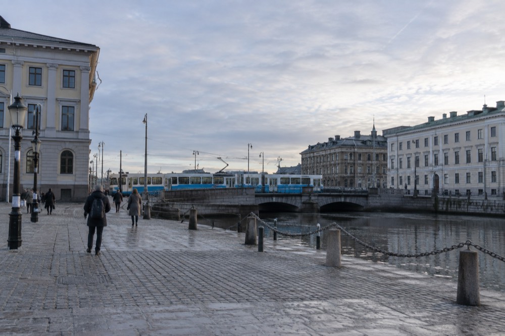 A blue Gothenburg tram crossing a stone bridge over the canal