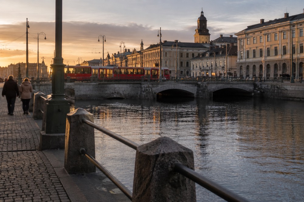 Red Gothenburg tram crossing a stone bridge over a canal in the evening