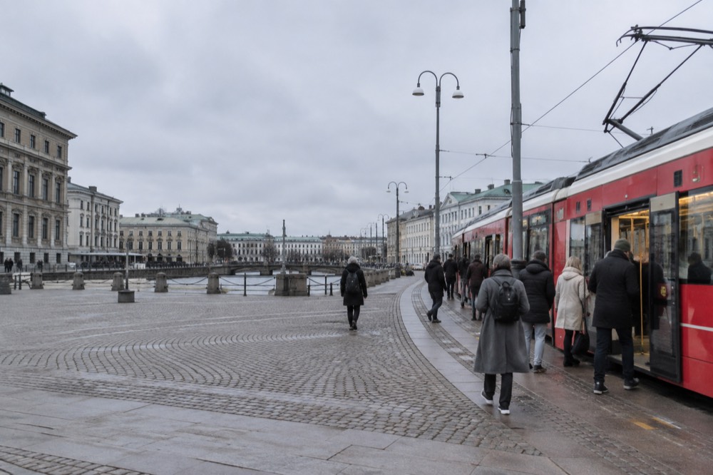 Passengers boarding a red tram at a central Gothenburg stop in daylight