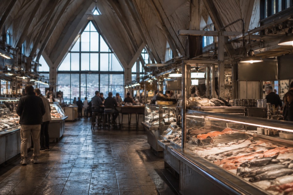 Interior of Feskekorka food hall in Gothenburg with fish counters and diners under the wooden roof