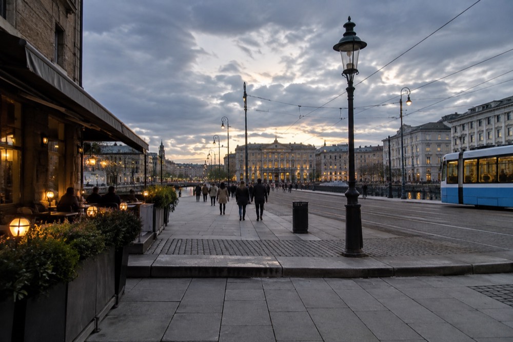 Wide city avenue at dusk with lit restaurants and a museum at its far end