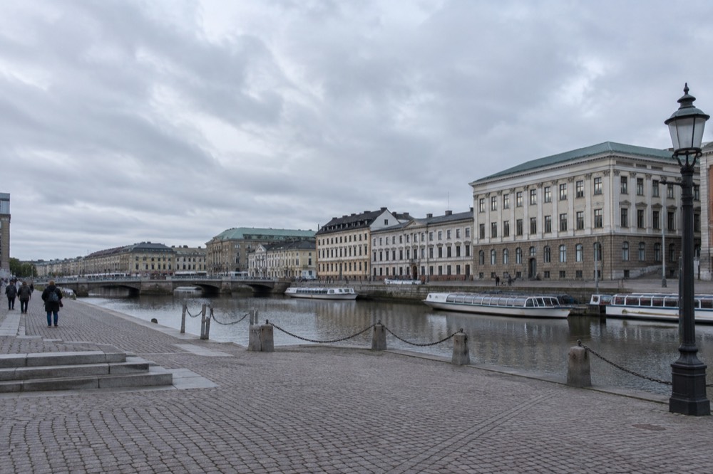 Gothenburg canal with sightseeing boats and stone buildings under a grey sky